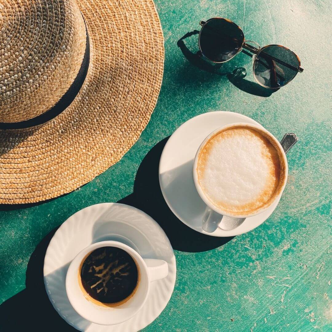 Restaurant table with an italian coffee, sunglasses & sun hat
